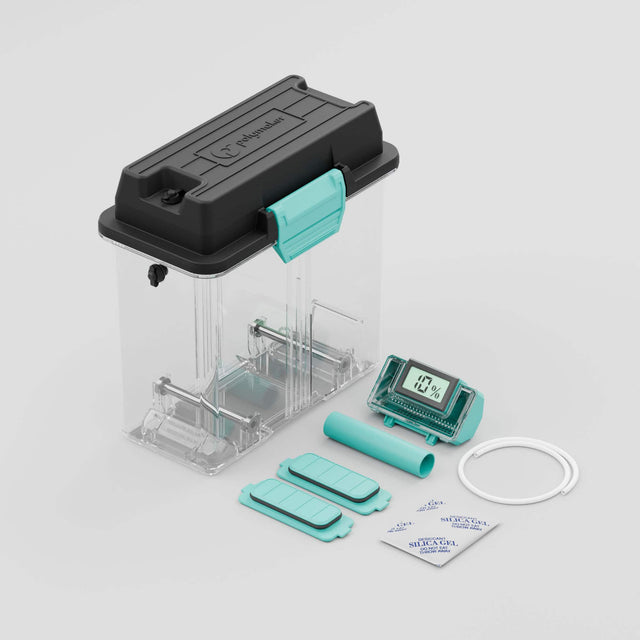 The image shows a small machine with a blue lid and a clear plastic container. The machine is accompanied by a blue tube and a white cord. The machine is designed for a specific purpose, which is not clear from the image. The text on the image reads "polymer L 1% IL 1% ciss. cms SDI MILACH  FORLON A - A SILICA GEL 1OR A NTa A." This text does not provide any information about the machine's function or purpose.
